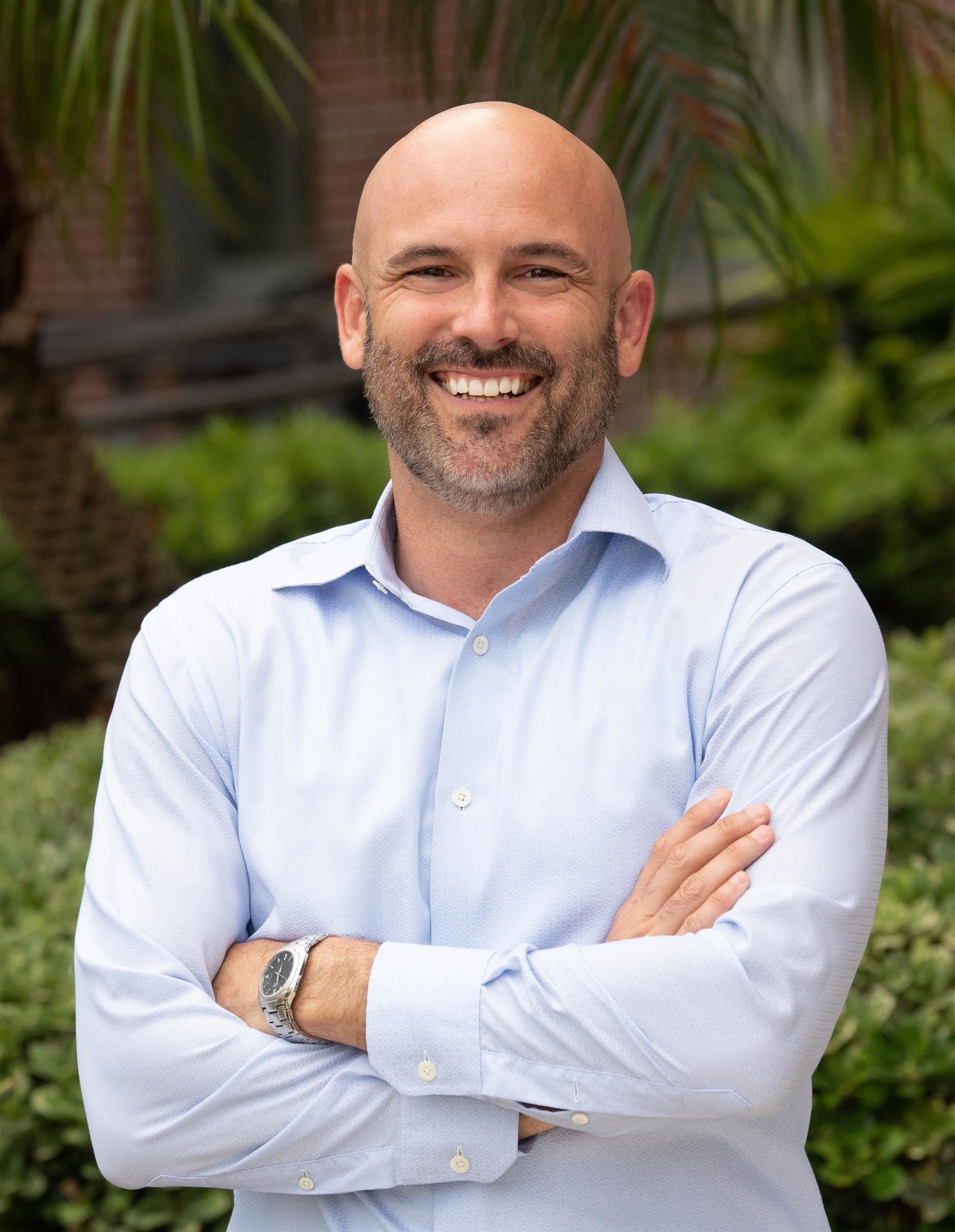 Principal Smith with a white collared shirt and light beard smiling with arms crossed