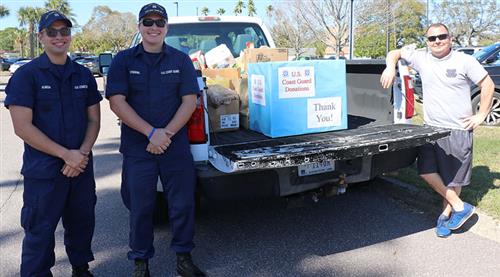 Coast Guard members stand with donations. 
