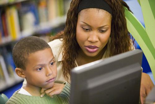 Teacher works with student on computer. 
