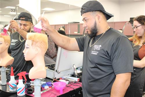 Student cutting a mannequin's hair. 