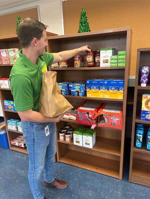 Mr. Reid Reynolds stocks Food Pantry shelf.