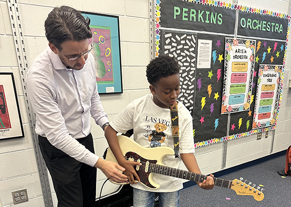 Perkins Elementary Principal Dr. Moss teaches a student how to rock out on the guitar.